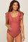woman wearing a rust-colored maternity swimsuit with ruffle sleeves and a visible baby bump