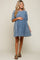 woman wearing a light blue denim maternity dress with short sleeves and a gathered waist, holding her baby bump