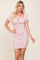 woman wearing a pink and white floral print smocked mini dress with puff sleeves and a sweetheart neckline