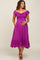 woman wearing a fuchsia off-the-shoulder maternity dress with a tie-front detail and ruffled hem, holding her baby bump