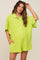 woman wearing a lime green short sleeve maternity romper with buttons and a collar