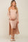 woman wearing a light pink maternity dress with ribbed texture and a matching long cardigan, cradling her baby bump