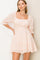 woman wearing a light pink eyelet mini dress with puff sleeves and a square neckline