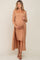 woman wearing a beige ribbed maternity dress with a matching long cardigan, holding her baby bump