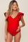 woman wearing a red ruffled maternity swimsuit with a v-neckline and a visible baby bump