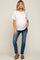 woman wearing a white short sleeve maternity top and blue jeans showing a visible baby bump