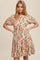 woman wearing a yellow floral puff sleeve mini dress with pink and red rose print