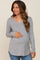 smiling pregnant woman wearing a grey long sleeve v-neck maternity top and blue jeans