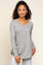 woman wearing a grey long sleeve v-neck t-shirt and light wash jeans