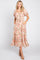 Woman wearing a blush pink floral midi dress with puff sleeves and a tie waist against a white background