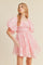 woman wearing a pink floral puff sleeve dress with a cinched waist and flared skirt
