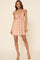 woman wearing a floral pink mini dress with ruffle sleeves and a tie front detail