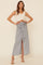woman wearing a white crop top with ruffle sleeves and a long light grey wrap skirt with a front tie detail
