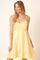 woman wearing a yellow sundress with tie straps and a ruffled hem