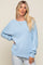 woman wearing a light blue oversized sweater with a wide neckline and slouchy sleeves, paired with light jeans