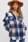 woman wearing a blue and cream plaid flannel shirt jacket with front pockets and a tan wide-brim hat