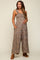 woman wearing a brown floral maternity jumpsuit with pockets, showing her baby bump