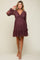woman wearing a burgundy maternity dress with a knot detail and balloon sleeves, showcasing her baby bump