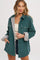 woman wearing a teal corduroy jacket with grey faux fur lining, button closures, and side pockets, styled with a tank top and shorts