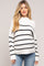 woman wearing a white and black striped maternity sweater with relaxed fit and long sleeves, showing her baby bump