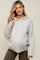 woman wearing a light gray maternity hoodie with cable knit sleeves and a visible baby bump