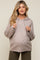 woman wearing a light beige maternity hoodie with cable knit sleeve details and a visible baby bump