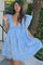 woman wearing a light blue short dress with puff sleeves and a deep v-neck, posing outdoors