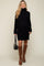 woman wearing a black ribbed maternity sweater dress with a turtleneck and knee-high brown boots, showcasing her baby bump