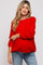woman wearing a red oversized maternity sweater with balloon sleeves and paired with light blue jeans