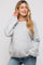 woman wearing a light gray maternity sweater with a relaxed fit and holding her baby bump