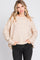 woman wearing a beige speckled oversized sweater with long sleeves and side pockets, paired with black jeans