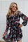 woman wearing a black floral ruffled dress with long sleeves and a tiered skirt