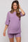 woman wearing a lavender maternity ribbed top and matching shorts, showing her baby bump