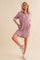 woman wearing a pink sequin oversized shirt dress with long sleeves and pockets, styled with white sneakers
