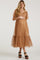 woman wearing a brown maternity dress with short tulle sleeves and a flowy skirt, holding her baby bump