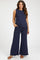 woman wearing a navy blue sleeveless maternity top and matching wide-leg pants, with hands in pockets