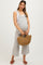 woman wearing a striped maternity jumpsuit with wide legs and holding a woven bag, showing a visible baby bump