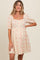 woman wearing a light beige short puff sleeve maternity dress with floral prints and a button-down front