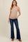 woman wearing a ribbed beige maternity tank top and dark blue flared jeans, showcasing her baby bump