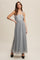 woman wearing a light gray spaghetti strap maxi dress with tulle overlay and pearl accessories, posing with gloves