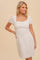 woman wearing a cream-colored short sleeve mini dress with a square neckline and puff sleeves