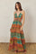 woman wearing a colorful maxi dress with a halter neckline and elastic waistband, standing against a textured background