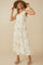 woman wearing a white floral maxi dress with tiered ruffles and a wide-brimmed hat