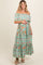 woman wearing a green floral off-the-shoulder maternity maxi dress and holding her baby bump