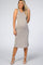 pregnant woman wearing a sleeveless tan and white striped maternity midi dress with white heels