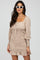 woman wearing a beige floral mini dress with puff sleeves and a ruffled hem, accessorized with white cat-eye sunglasses
