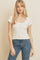 woman wearing a white ribbed short sleeve button-up top and blue denim jeans