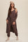 woman wearing brown lounge set with matching cardigan, beanie, and socks against a neutral background