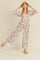 Woman wearing a floral puff sleeve jumpsuit with a straw hat and woven platform sandals