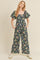 woman wearing a navy floral jumpsuit with puff sleeves and side pockets, styled with white sneakers